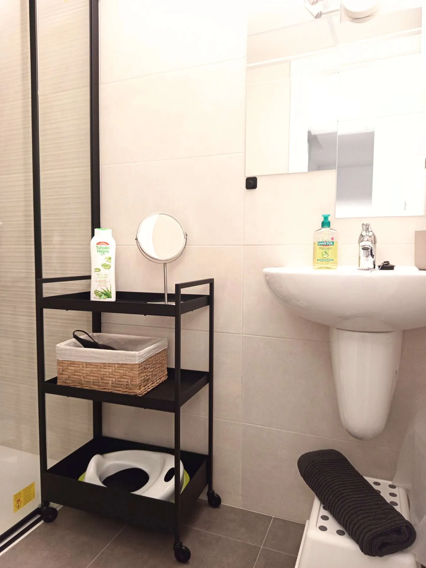 Druga łazienka — umywalka, lusterko kosmetyczne i wózek łazienkowy