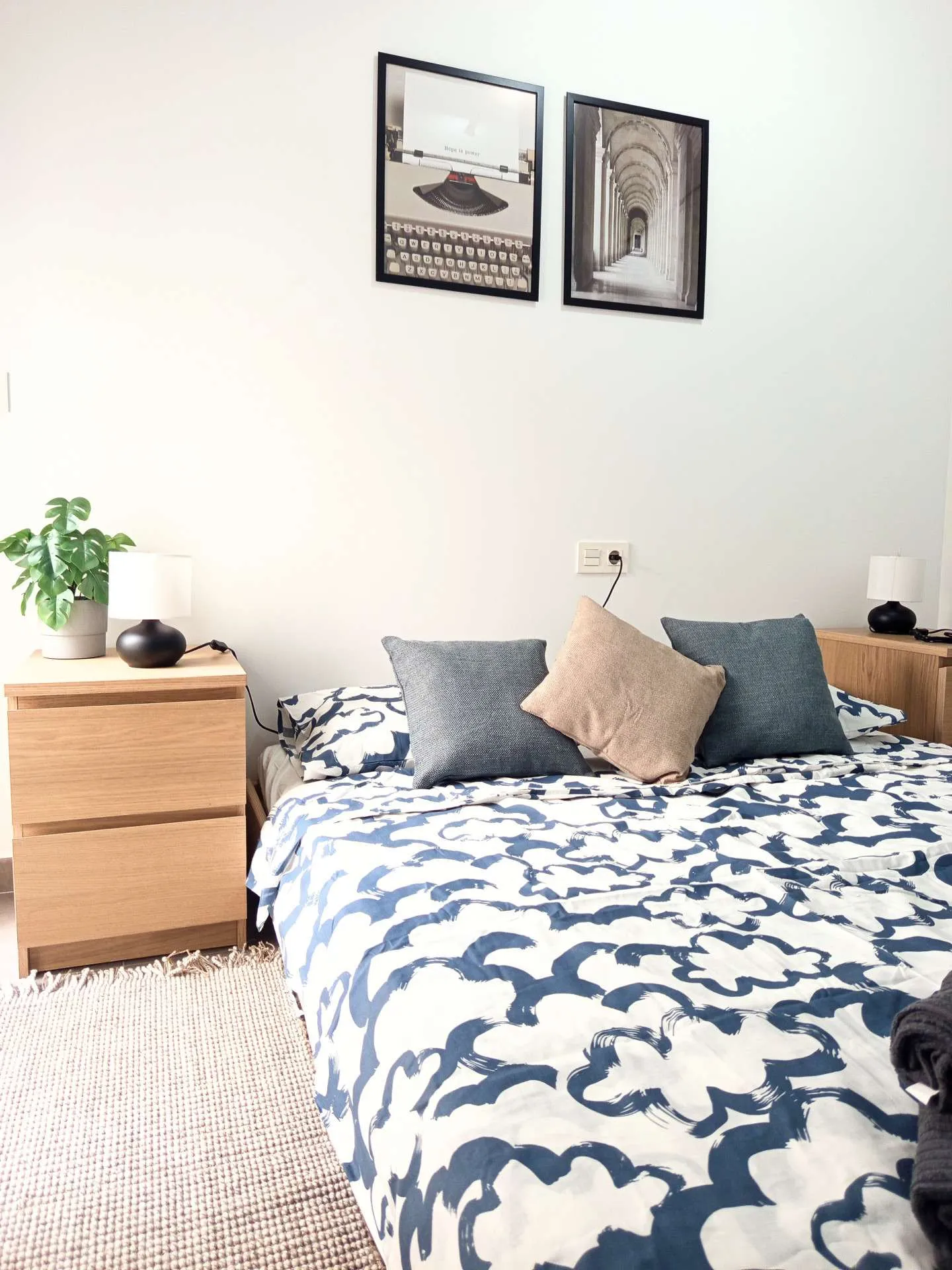 Druga sypialnia z obrazkami na ścianie, niebieską pościelą i drewnianymi szafkami