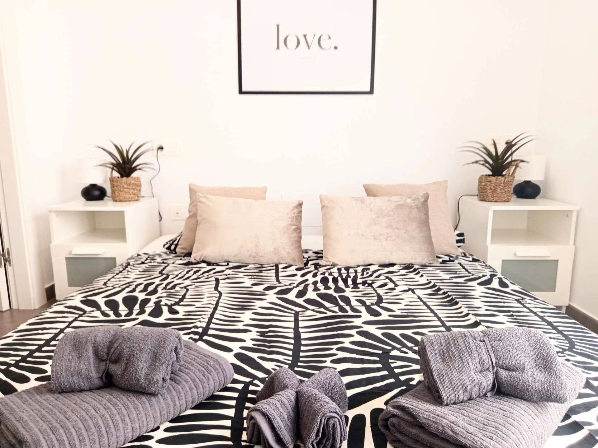 Sypialnia główna z ręcznikami, poduszkami i plakatem love — widok frontalny