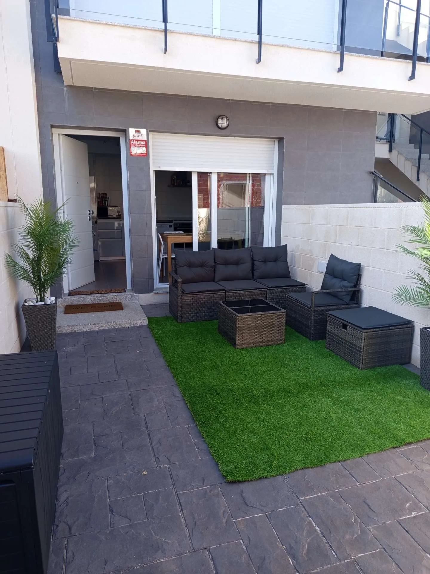 Taras z meblami ogrodowymi — widok z góry na wejście do apartamentu